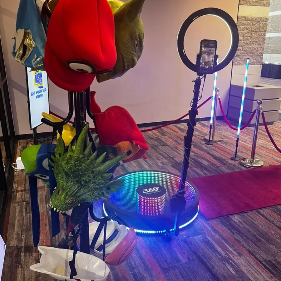 A Celebrate in 360 video booth set up at an event, with red carpet, stanchions and LED lighting
